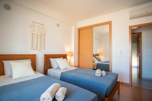 Ein Hotelzimmer mit zwei Betten, einem Spiegel und einer Tür zu einem weiteren Raum.