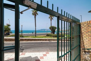 Een poort met uitzicht op zee, palmbomen en een heldere lucht.