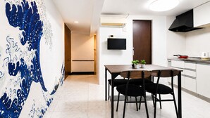 Eine moderne Küche mit Flachbildfernseher, Herd und Essbereich mit Tisch und Stühlen.