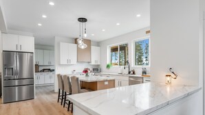 A modern kitchen with a large island, stainless steel appliances, and a view of the outdoors.