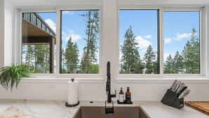 A modern kitchen with a large window, a built-in sink, and a knife block.