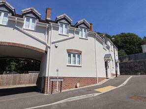 A two-story house with a brick facade, white windows, and a covered driveway. - L'ancresse Cottage (Lyme Regis)