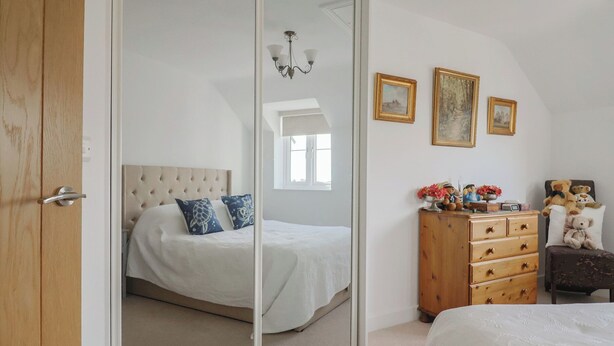 Um quarto com uma cama, uma cômoda e um espelho.