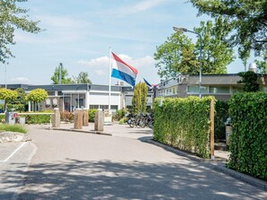 Ein Gebäude mit einer Flagge, einem Fahrrad und einer Hecke.