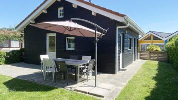 A house with a patio, a table with chairs, and a large umbrella.