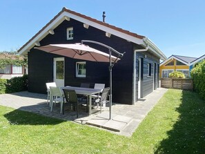Ein Haus mit Terrasse, einem Tisch, Stühlen und einem großen Sonnenschirm.