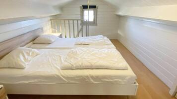 A single bed in a room with white walls and wooden flooring.