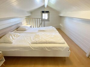 Ein Einzelbett in einem Zimmer mit weißen Wänden und Holzboden.
