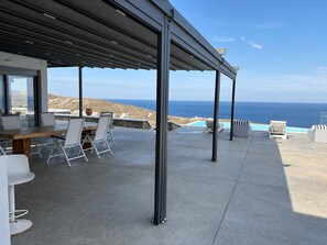 A covered outdoor area with a pool, seating, and a view of the ocean.