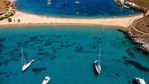 A coastal area with clear turquoise waters, boats, and a sandy beach. - Kythnos Luxury Villa Aegean View Private Pool Gem (Kithnos)