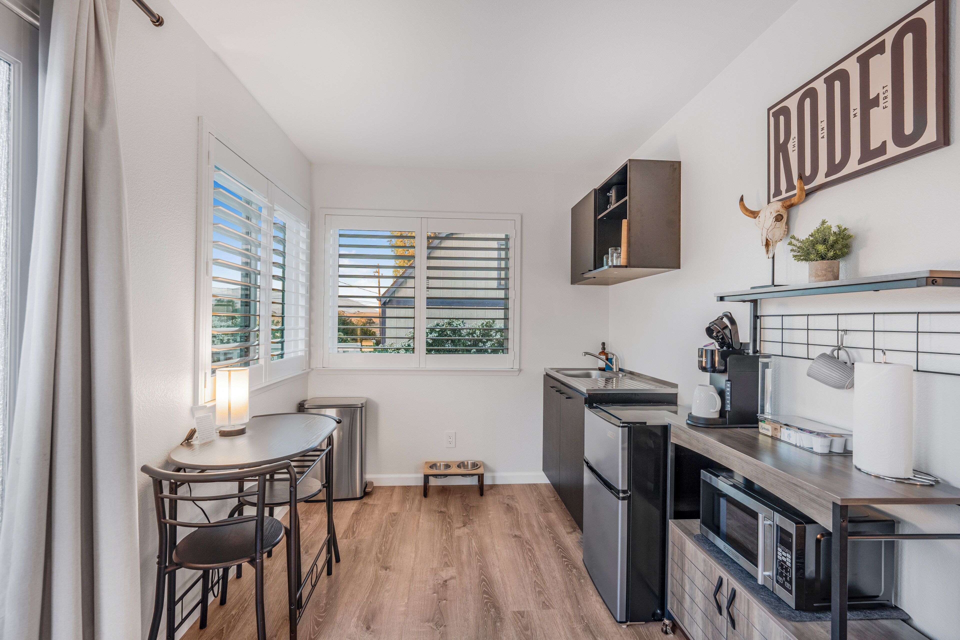 Una cocina compacta con comedor, un espacio pequeño para dar de comer a mascotas y un letrero en la pared.