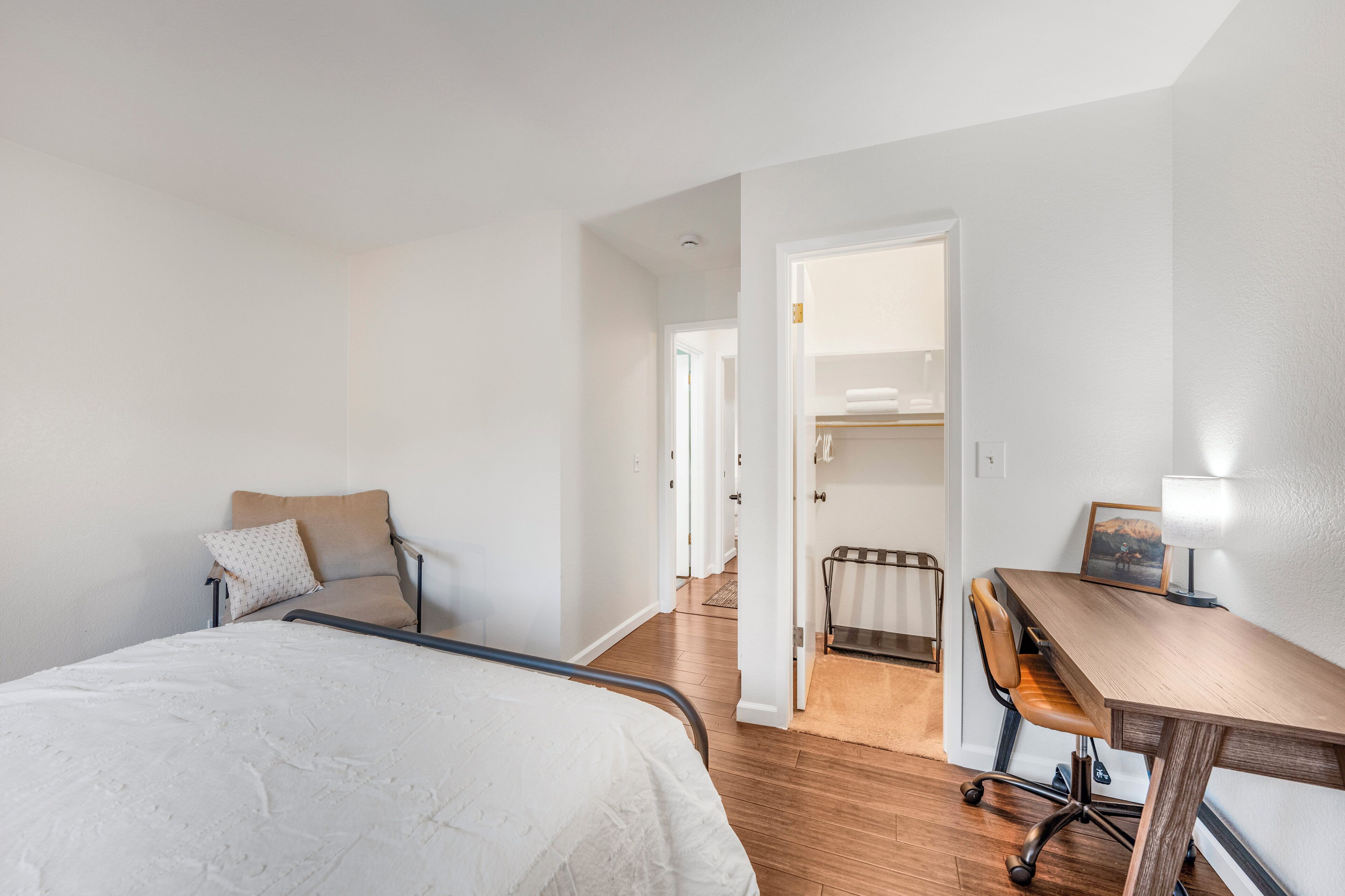 Une chambre d’hôtel comprenant un lit, un bureau, une chaise et un dressing.