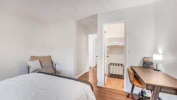 Une chambre d’hôtel comprenant un lit, un bureau, une chaise et un dressing.