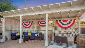An outdoor patio with a covered seating area, a stone fountain, and decorative string lights.