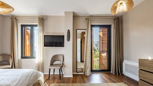 A bedroom with a bed, a chair, a TV, a large mirror, and a view of the outside. - Villa Bora No 7 Belvedere Kor a (Qendër Bulgarec)