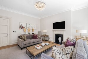 Ein Wohnzimmer mit einer Couch, einem Couchtisch, einem Kamin und Kunstwerken an der Wand.