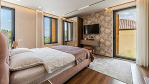 Une chambre moderne avec un grand lit, un téléviseur à écran plat et un mur en pierre.