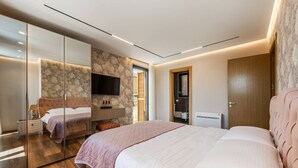 Une chambre moderne avec un grand lit, un miroir, une télévision et un mur décoratif en pierre.