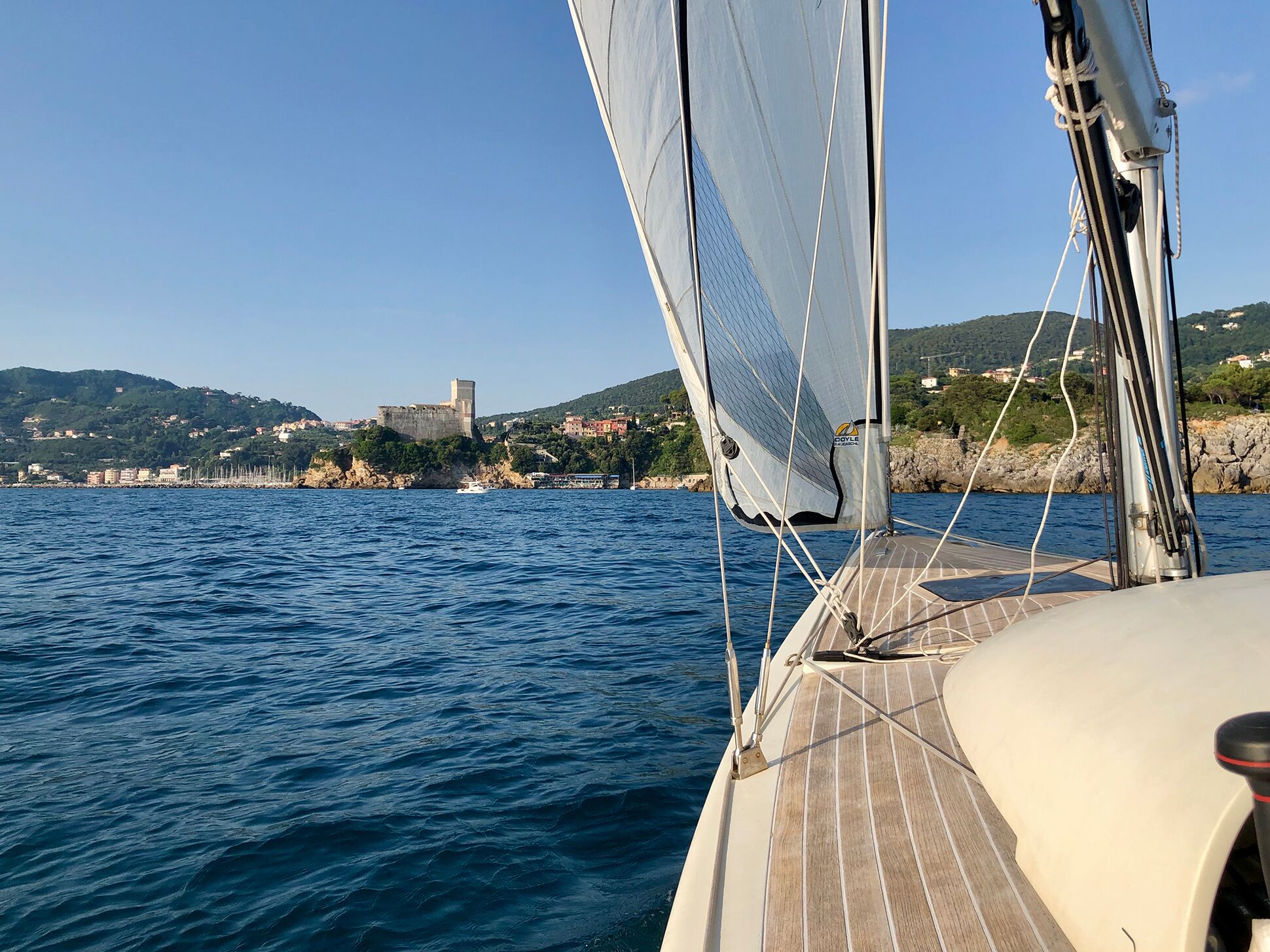 Un velero con vistas a un pueblo costero y un castillo al fondo.