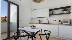A modern kitchen with a dining table, chairs, a bowl of fruit, a microwave, and a potted plant. - Domus Sagari - Suite Executive (Presicce)