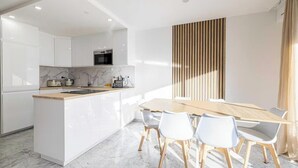 A modern kitchen with white cabinetry, a wooden island, and a dining area with a wooden table and chairs. - PERFECTLY POSITIONED FOR DISCOVERING THE CITY'S VIBRANT ATMOSPHERE ON FOOT (Cannes)