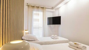 A hotel room with two beds, a flat-screen TV, a lamp, and a window with curtains. - PERFECTLY POSITIONED FOR DISCOVERING THE CITY'S VIBRANT ATMOSPHERE ON FOOT (Cannes)