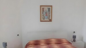 Ein Schlafzimmer mit einem Bett, einem Nachttisch, einer Lampe und einem Wandbild.