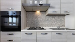 Una cocina moderna con horno empotrado, cocina a gas y muebles altos de acero inoxidable.