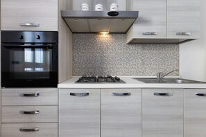 A modern kitchen with a built-in oven, a gas stove, and stainless steel cabinets.