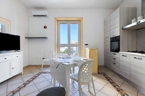Une cuisine moderne avec des armoires blanches, un four encastré et un coin repas comprenant une table et des chaises.