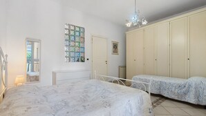 Un dormitorio con una cama grande, dos camas individuales, un armario, un espejo y un cuadro en la pared.