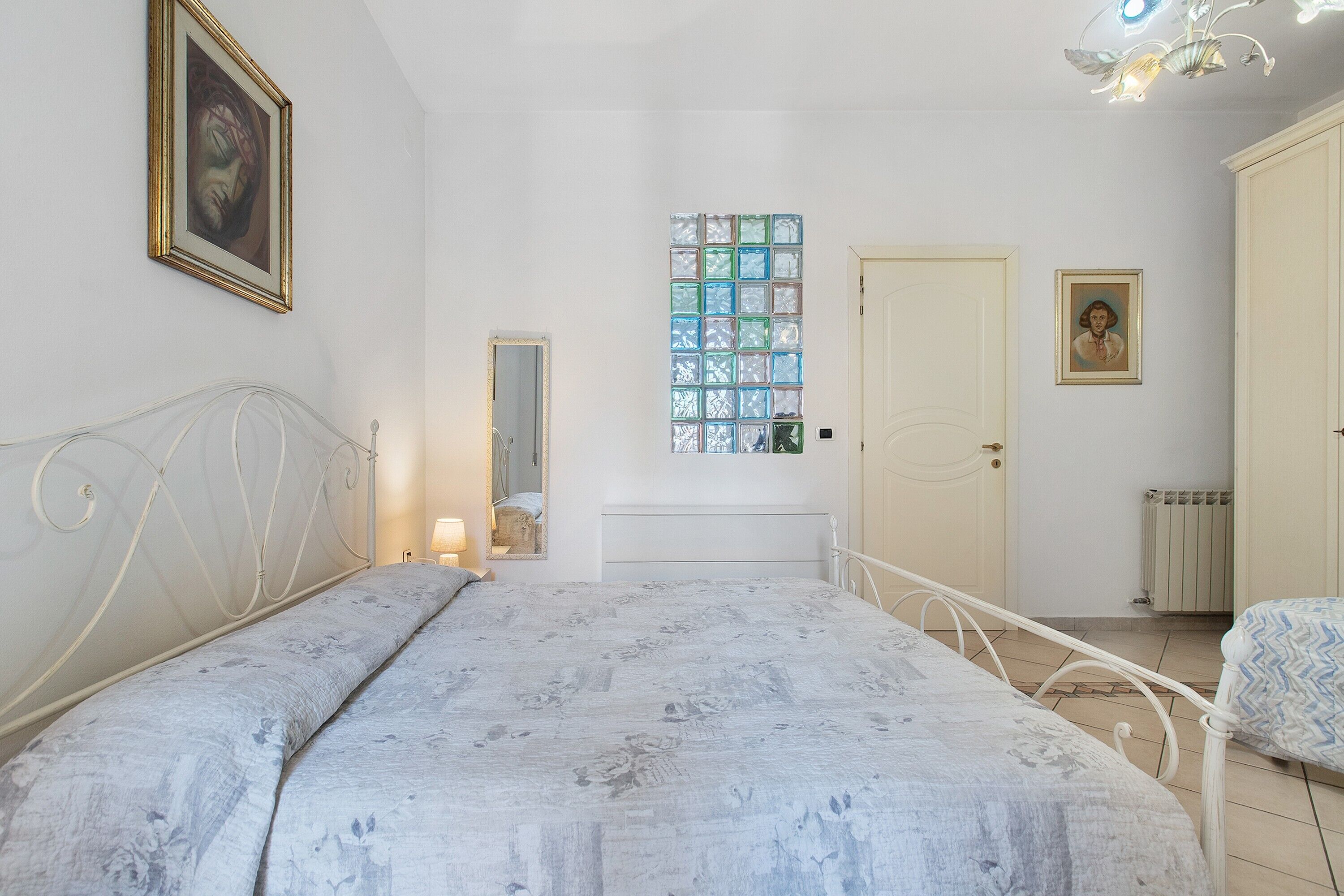 Ein Schlafzimmer mit einem Bett, einem Fenster mit Buntglasdekor, einer Tür und einer Heizung.