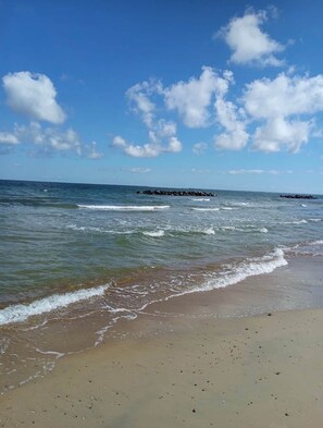 A beach with waves, a clear sky, and a distant pier. - The SEA-renity cozy apartment across from the beach (Norfolk)