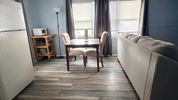 A compact living space with a kitchenette, a dining table with chairs, and a sofa.