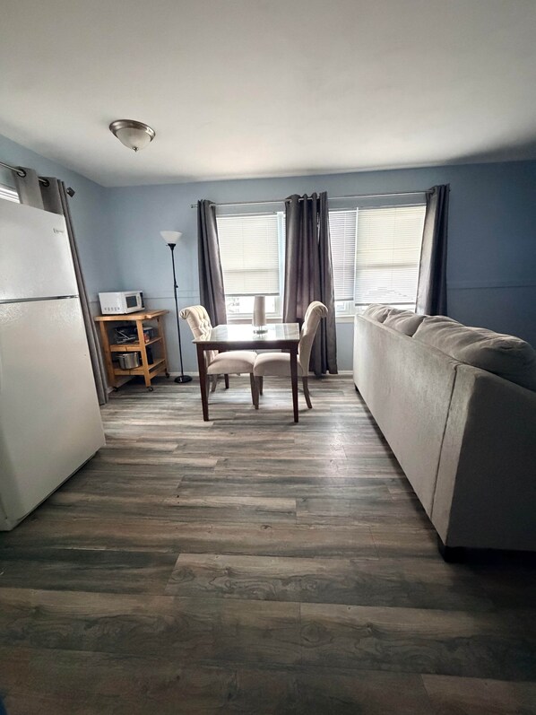 Un espacio habitable compacto con kitchenette, una mesa de comedor con sillas y un sofá.