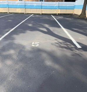Un parking avec des places délimitées et une clôture blanche en arrière-plan.