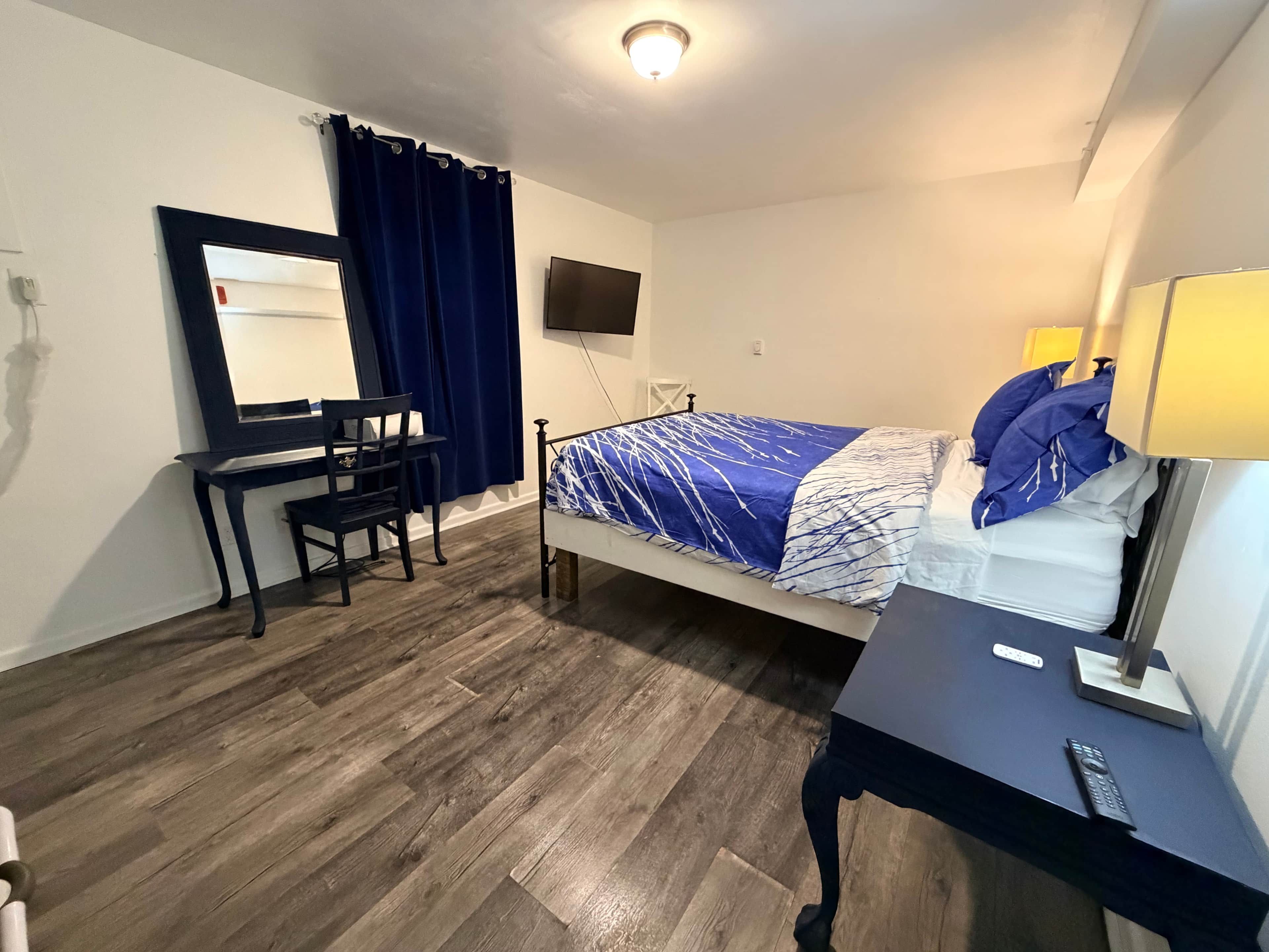 Un dormitorio con una cama, un escritorio, una silla, un televisor y una lámpara.