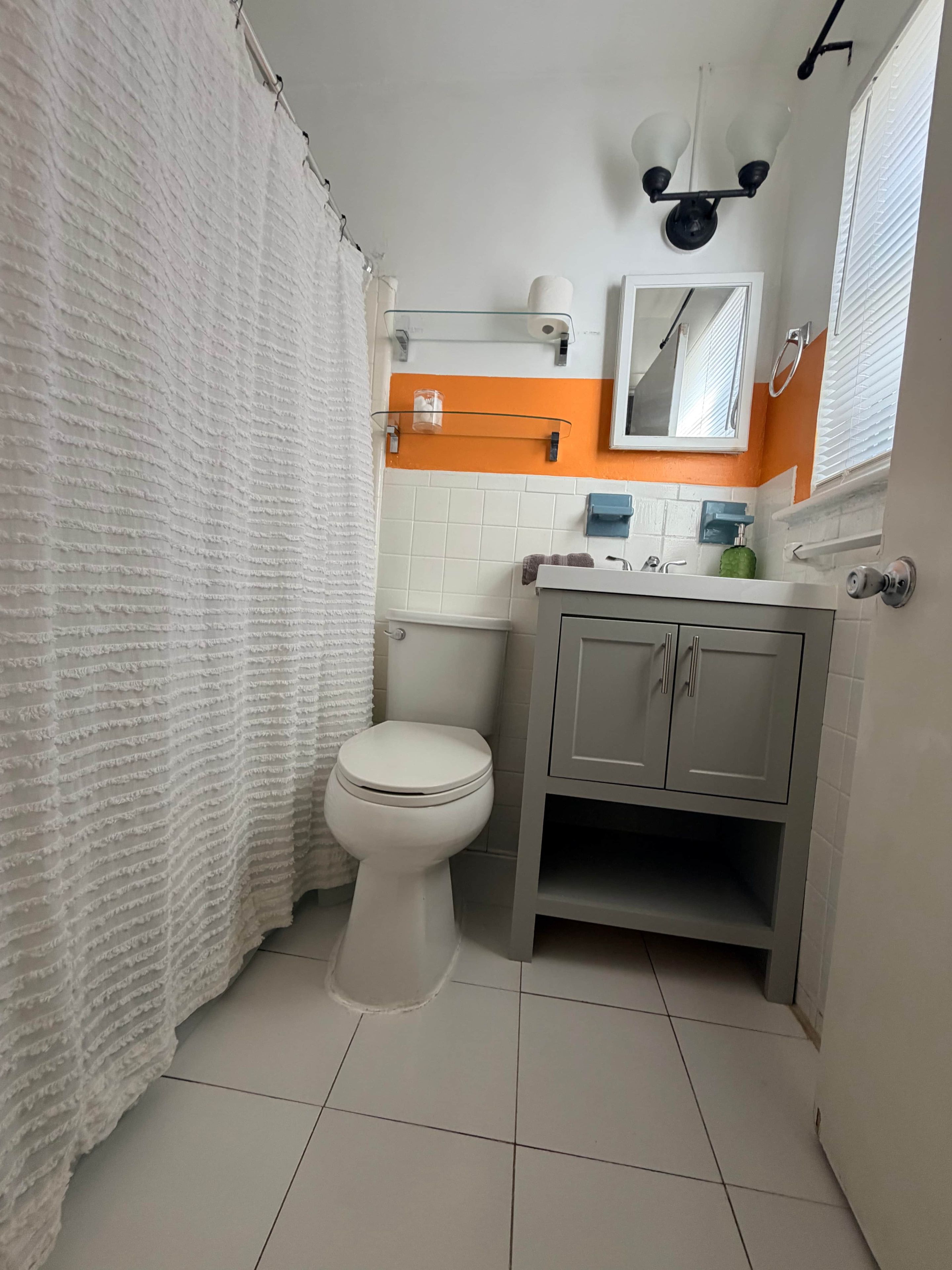 A bathroom with a toilet, a sink, a mirror, and a shower curtain.