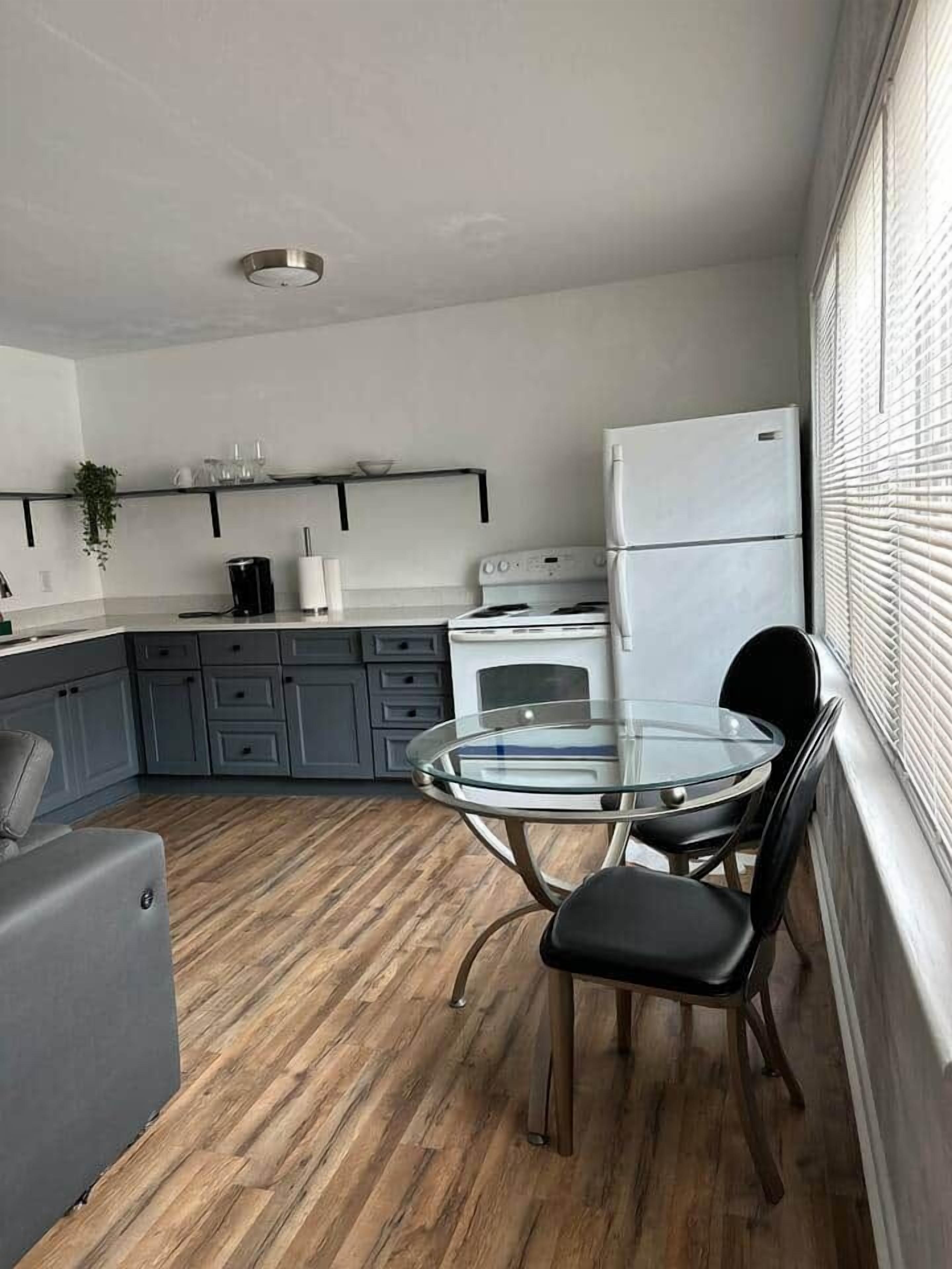 Een kleine keuken met een koelkast, fornuis en moderne kastjes.
