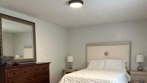 Ein Schlafzimmer mit Bett, Schminktisch, Nachttischen und Spiegel.