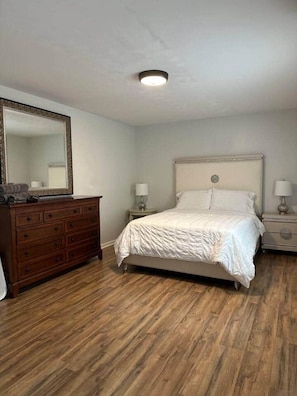 A bedroom with a bed, dresser, nightstands, and a mirror. - SEA-renity 13 cozy apartment across from the beach (Norfolk)