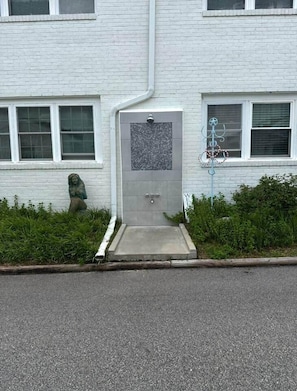 A building with a white facade, a door with a small window, and a statue of a figure. - SEA-renity 13 cozy apartment across from the beach (Norfolk)