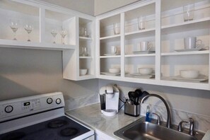 Une cuisine avec des meubles blancs, une cuisinière, une machine à café et un évier.