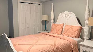 A bedroom with a bed, nightstand, lamp, and a door.