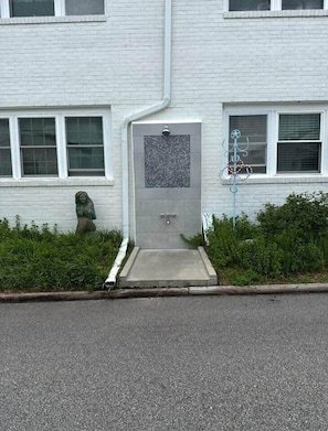 Un edificio con fachada blanca, una puerta con un pequeño ventanal y una estatua de una figura.
