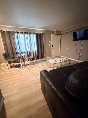 Una sala de estar con un sofá, una mesa de comedor y un televisor montado en la pared.