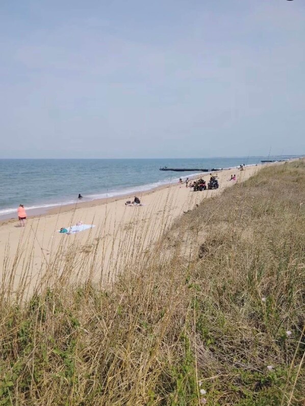 A beach with people and ATVs, a clear sky, and a calm sea. - The SEA-clusion 8 cozy apartment across from the beach (Norfolk)