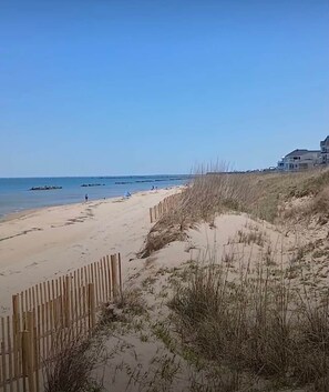 A sandy beach with a wooden fence, grassy dunes, and a clear blue sky. - The SEA-clusion 8 cozy apartment across from the beach (Norfolk)