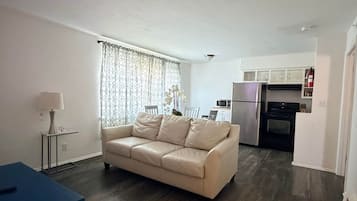 A living room with a sofa, a coffee table, and a kitchen area with appliances.