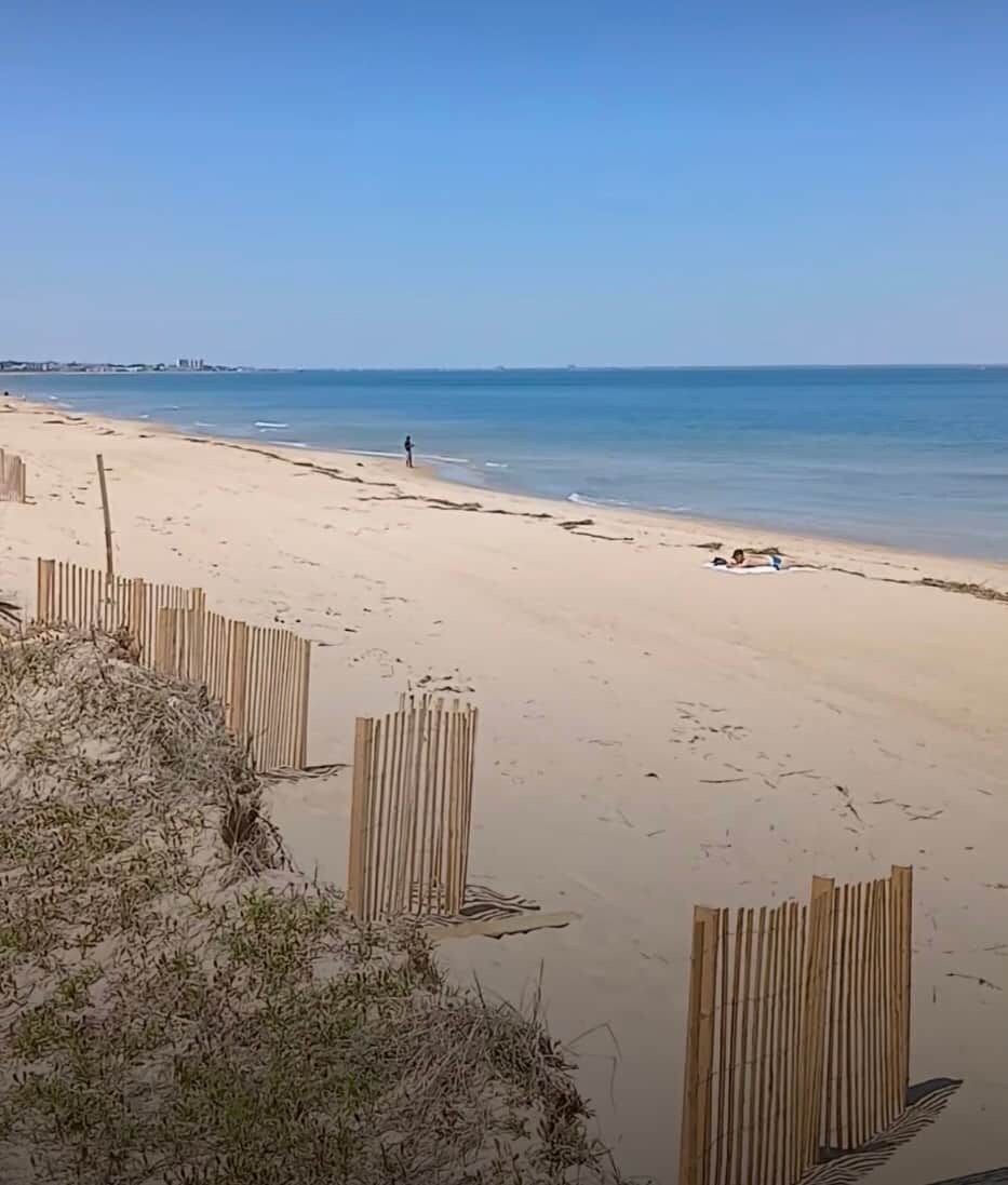 Een strand met een houten omheining, zandstrand en rustige zee.